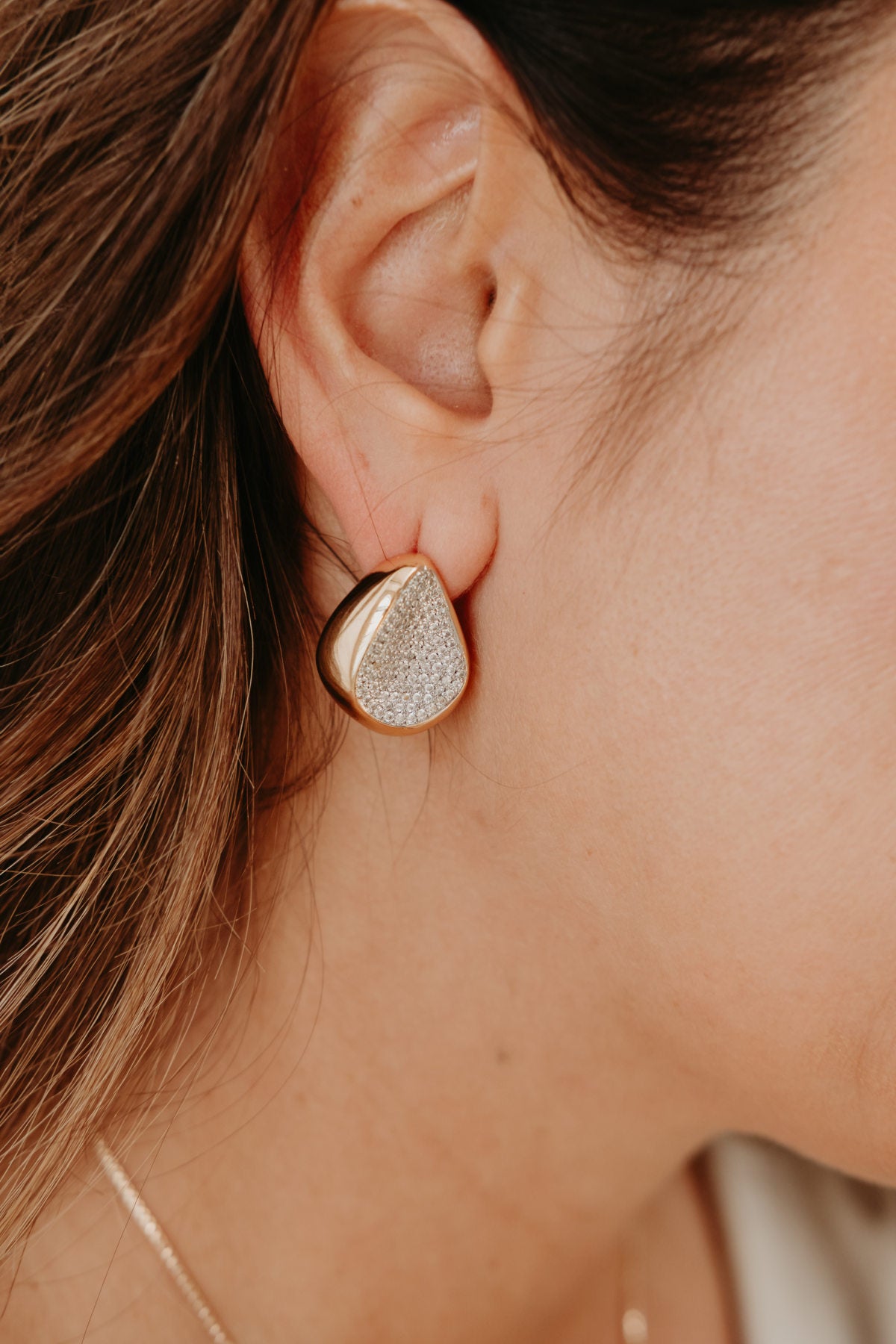 Sculptural gold earrings featuring a polished finish and textured clear zirconia center accents